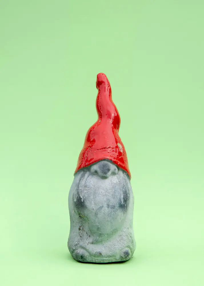Garden gnome with red pointed hat covering eyes