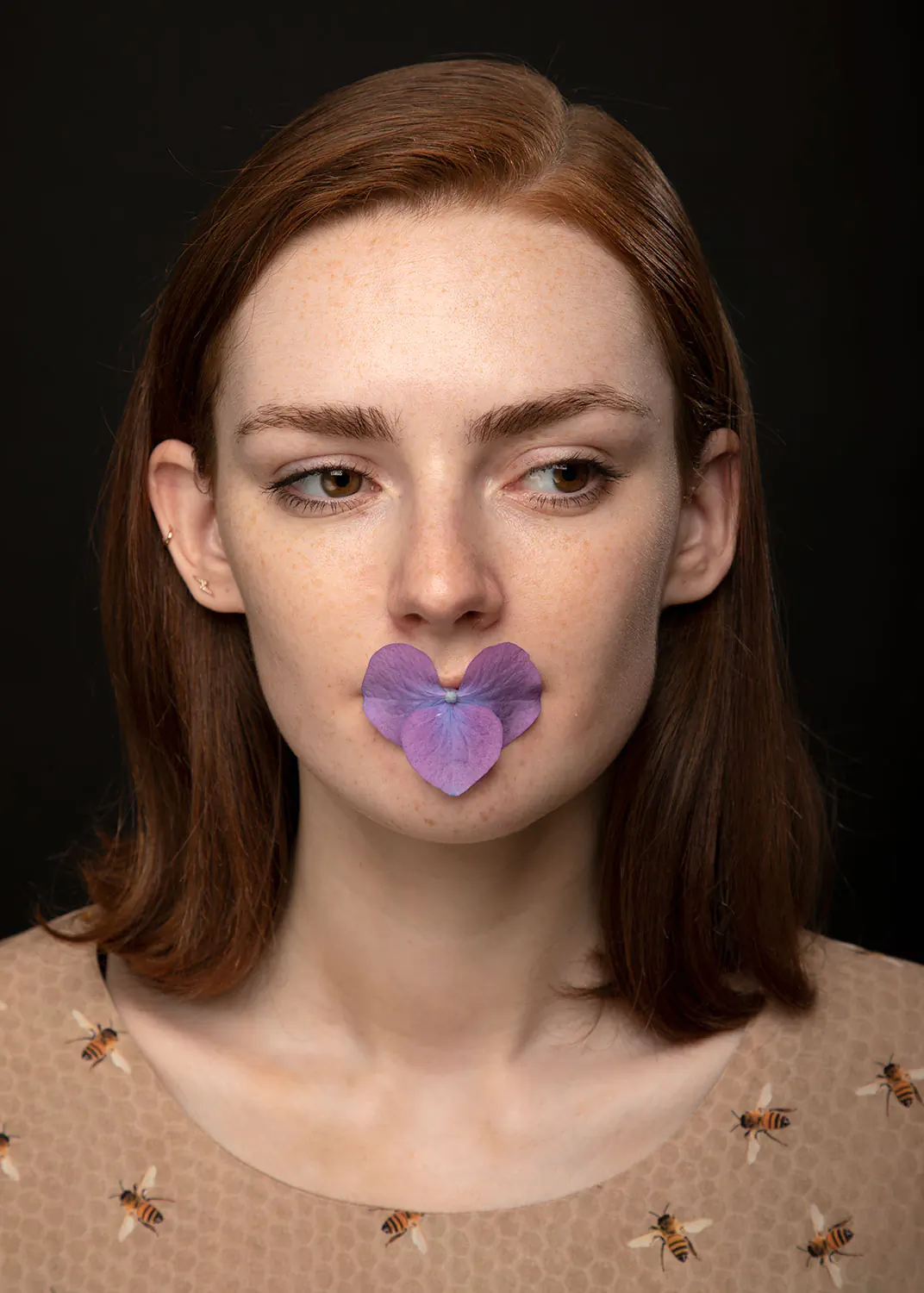 Artistic portrait of a woman with purple hydrangea flowers in mouth