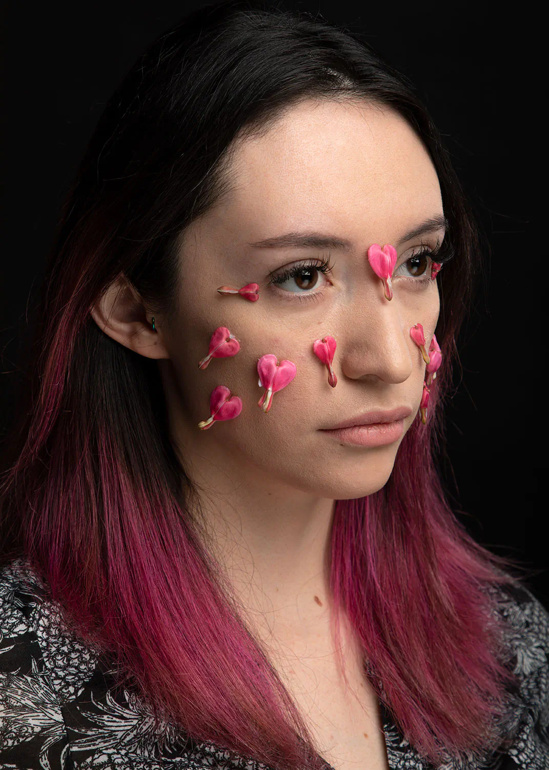 Creative portrait with heart flowers on a young woman's face