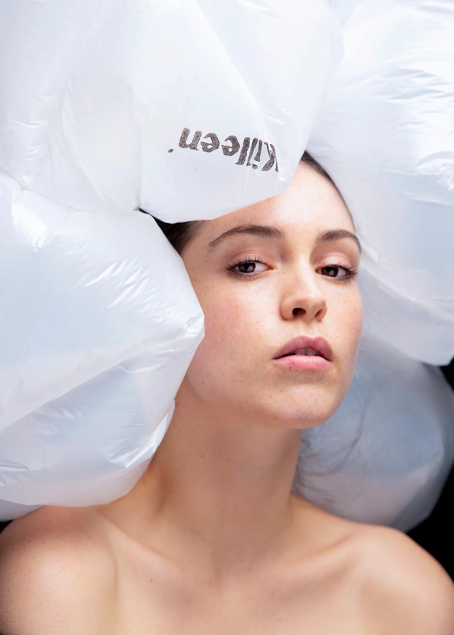 Single-use plastic bags as headpiece on a young woman