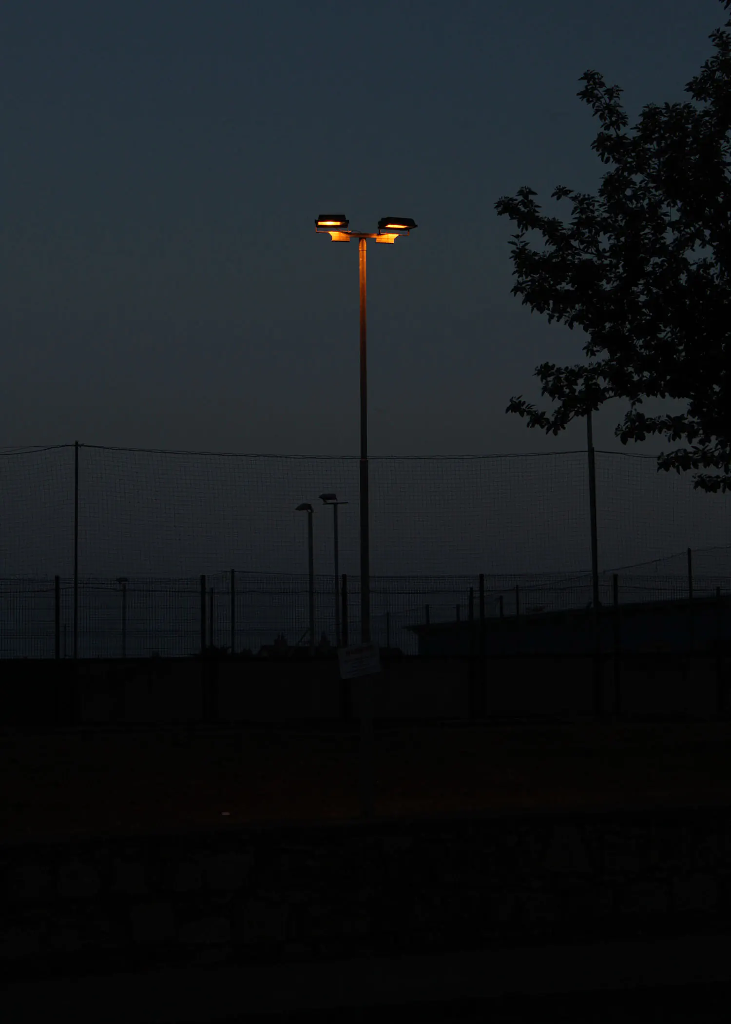 Lamppost in the dark in front of football pitches
