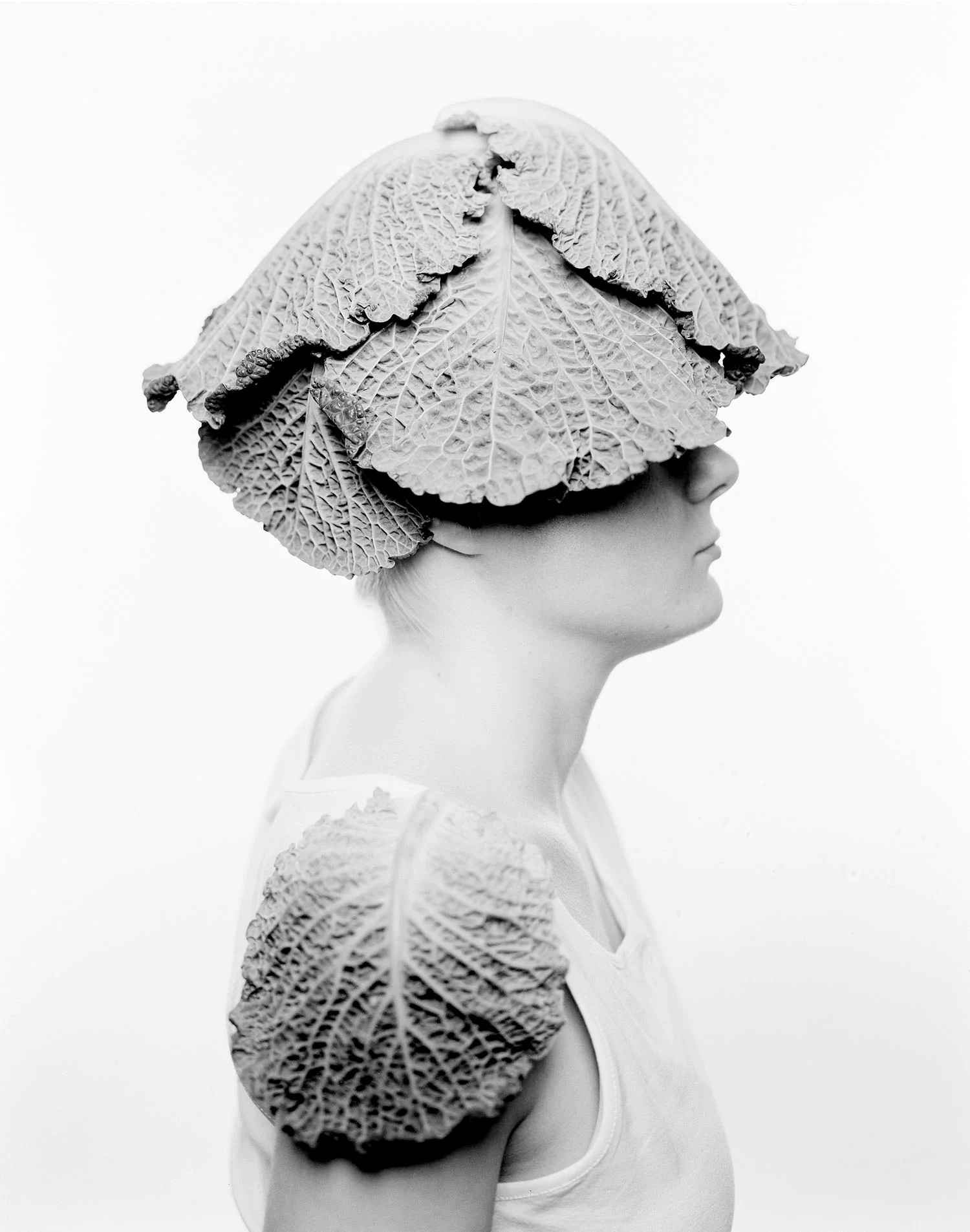 Large format portrait of young woman with cabbage leaves as head gear and shoulder pads