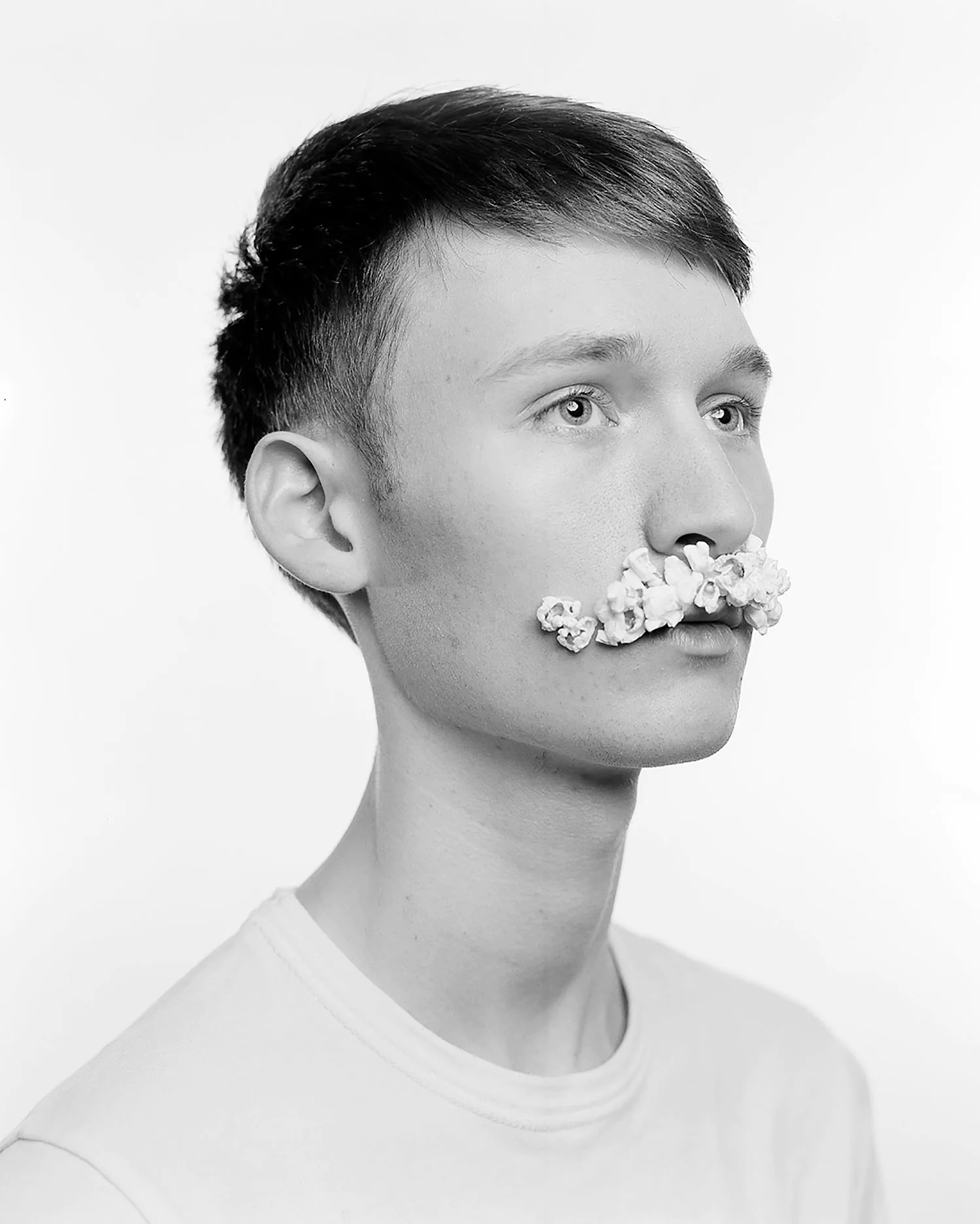 Large format black and white portrait of young man with popcorn as moustache